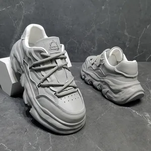 Detailed view of grey men's chunky sneakers with a thick melting sole on marble background.