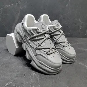 Close-up of grey leather chunky sneakers with a unique thick dissolved sole design.