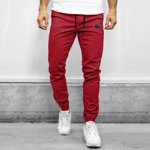 Detail view of men's red joggers with elastic cuffs and black drawstring waist
