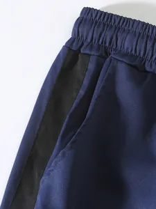 Close-up detail of navy blue men's cargo pants with black side stripe and elastic waist