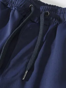 Close-up of navy blue cargo pants waistband with elastic drawstring and metal tips