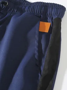 Close-up detail of navy blue cargo pants with elastic waist and side stripe