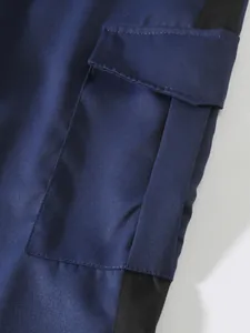 Macro close-up view of the cargo pocket detail on navy blue patchwork men's trousers