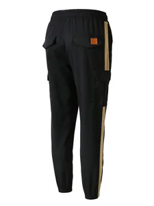 Rear view of black men's cargo pants with tan side stripe and flap pockets detail.