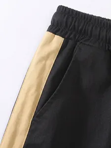 Close-up detail of black cargo pants with elasticated waist and beige side stripe