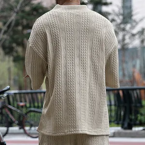 Detailweergave van de ingewikkelde kabelbreistructuur op de rug van een beige heren T-shirt