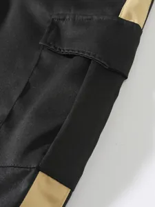 Close-up of black cargo pants pocket with side tan stripe and fine stitching detail
