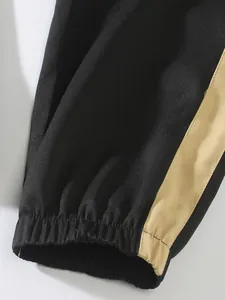 Detail view of elasticated cuff on black men's cargo pants with khaki side stripe