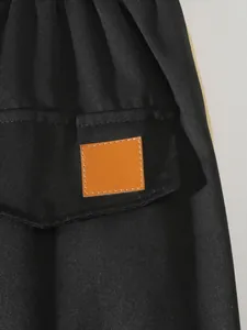 Detail view of black cargo pants pocket with a stylish brown faux leather patch detail.