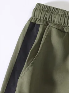 Macro view of olive green men's cargo pants showing elastic waistband and pocket detail.