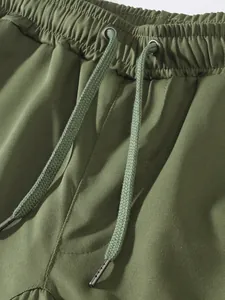 Close-up of men's cargo pants waistband with green drawstring and metal eyelets.