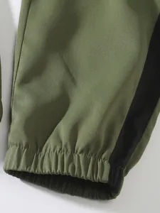 Close-up of olive green cargo pants featuring elastic cuffs and black side stripes