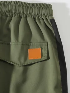 Detail view of men's olive green cargo pants with elastic waist and pocket detail.