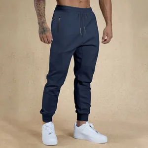 Close-up of men's navy blue athletic joggers with drawstring waist and zipper pocket.