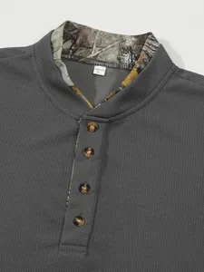 Detailansicht von dunkelgrauem Waffelstrick-Poloshirt mit Camouflage-Kragen und Knöpfen.