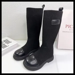 Dettaglio di stivali alti in maglia elastica nera per bambina con punta in pelle.