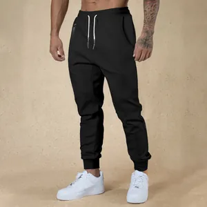 Detail view of men's black drawstring joggers with ribbed cuffs and white cords