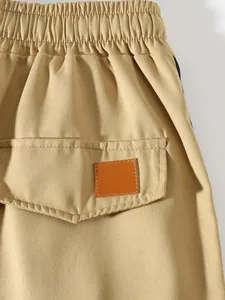Macro detail of khaki cargo pants featuring elastic waistband and back pocket flap