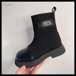 Dettaglio degli stivaletti a calza in maglia nera per bambini con materiale elastico.