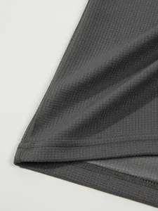 Detailaufnahme der dunkelgrauen Waffelstrick-Stoffstruktur und des Saums am Herren-Poloshirt