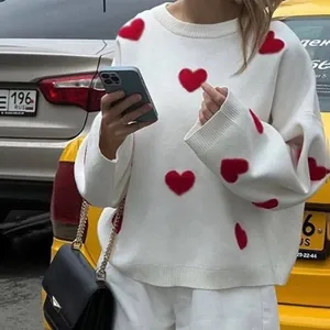Nahaufnahme eines weißen Strickpullovers mit leuchtend roten Herzmustern für Damen