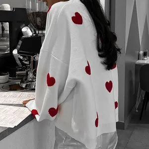 Detailansicht eines weißen Oversize-Strickpullovers mit roten Herzen im Café-Look