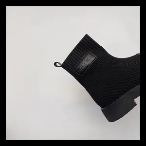Dettaglio degli stivali a calzino in maglia nera per bambine con toppa logo Miki