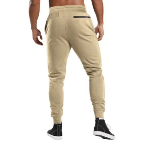 Detailed back view of men's beige joggers with a black zipper pocket and ribbed cuffs.