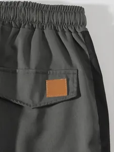Detail view of men's casual cargo pants featuring elastic waist and pocket patch