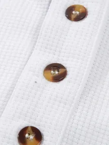 Nahaufnahme eines weißen Waffel-Poloshirts für Herren mit braunen Knöpfen