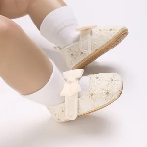 Détail de chaussures de princesse bébé en dentelle blanche avec broderies et nœuds.