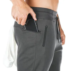 Close-up of men's charcoal grey joggers featuring zippered pocket and gym towel loop