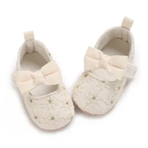 Gros plan de jolies chaussures de princesse bébé avec dentelle blanche et gros nœud.