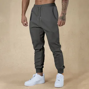 Close-up of men's dark gray drawstring joggers with zipper pocket and elastic cuffs.