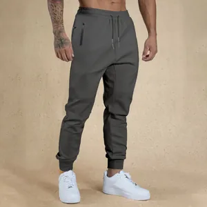 Close-up of men's charcoal gray drawstring joggers featuring zippered pockets and slim fit design