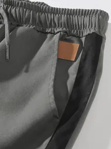 Close-up detail of gray cargo pants showing elastic waistband, drawstring, and leather patch.