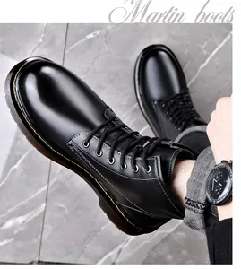 Close-up van zwarte leren Martin boots met gele stiksels en vetersluiting detail.