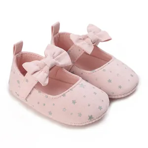 Close-up of pink baby princess shoes with a bow detail and silver star pattern on soft fabric