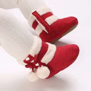 Detailed close-up of red infant winter boots featuring plush lining and cute pom-poms