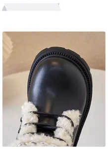Detail of children's black Martin boots featuring soft white faux shearling trim.