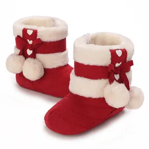 Detail view of red baby winter boots featuring white faux fur trim and cute pom-poms.