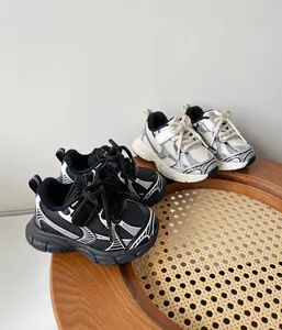 Zapatillas deportivas para niños pequeños y zapatos daddy en blanco y negro sobre un taburete
