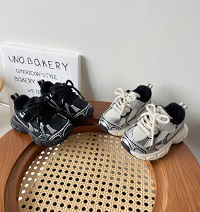 Zapatillas deportivas para niños en blanco y negro sobre una silla de madera y mimbre