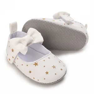 Detail view of white baby girl princess shoes with gold star patterns and soft sole