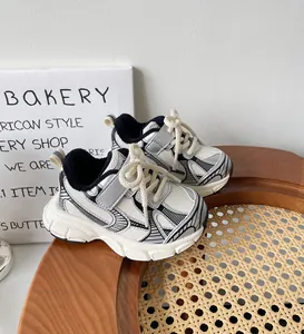 Vista detallada de zapatillas chunky para niños en blanco y negro sobre taburete.
