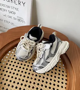 Vista detallada de zapatillas tipo chunky para niños en color crema sobre silla de mimbre