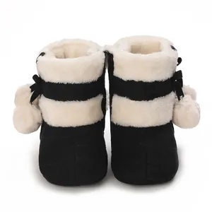 Close-up view of cozy black and white baby winter plush boots with cute pom-pom accents