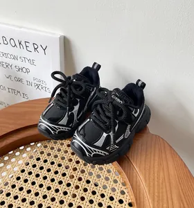 Vista detallada de zapatillas chunky blancas y negras para niños en silla madera