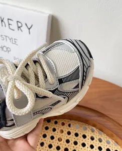 Detalle de zapatillas deportivas transpirables para niños en malla plateada y blanca