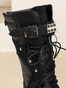 Detailansicht von schwarzen Punk-Keilstiefeln mit Schnallen, Metallring und Nieten